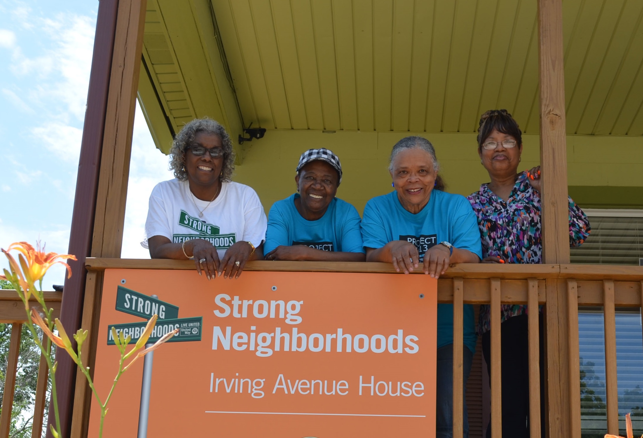 Four Black women leaning on the porch railing of Irving Avenue House