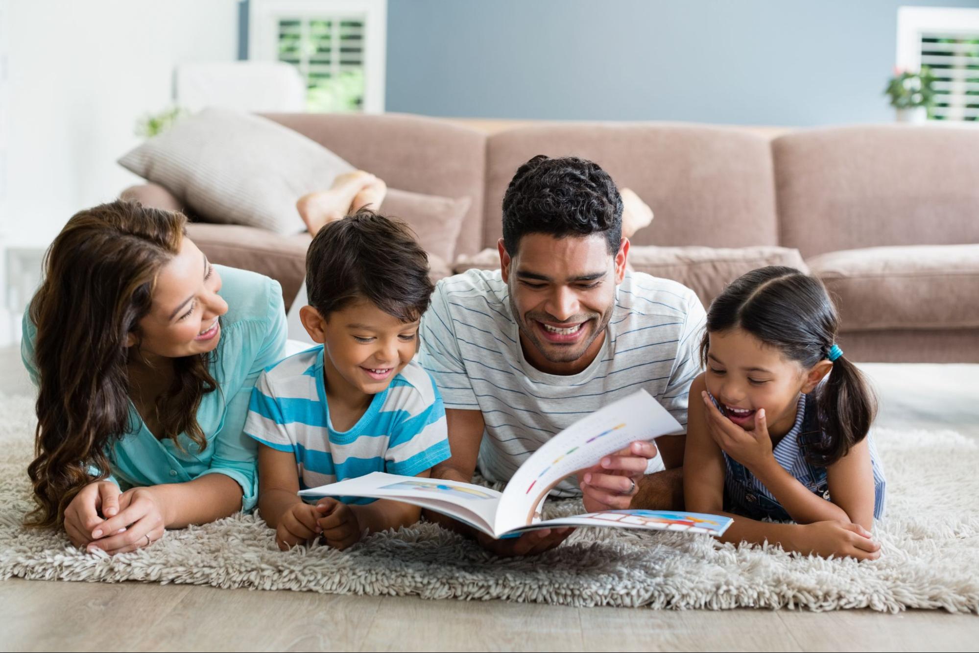 Parents and children lying on rug reading story book together
