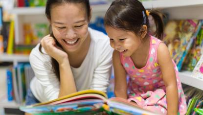 Mother and daughter smiling while reading together