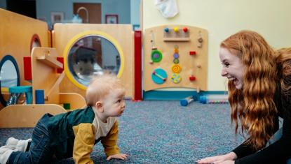 woman plays with baby on the floor